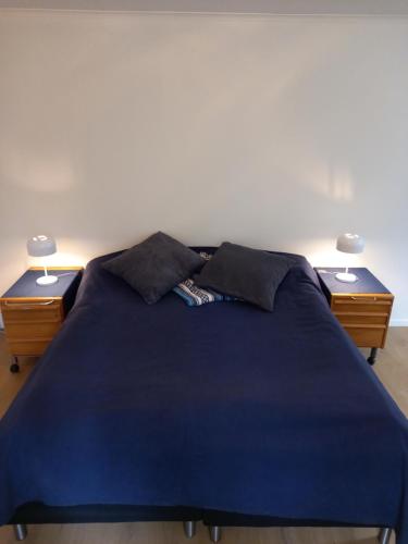 a blue bed with two nightstands and two lamps at Easystar guest house in Ingarö