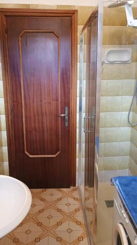 a bathroom with a shower and a wooden door at Domus amica 1 in Finocchito