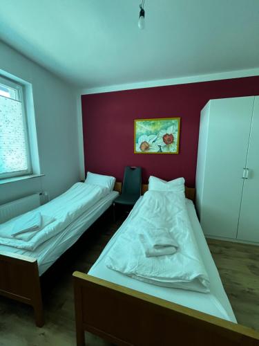 two beds in a room with a red wall at Ferienwohnung Fatlume No 5 n 6 in Bad Honnef am Rhein