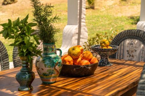 a bowl of oranges on a wooden table with vases at Finca Santa Teresa, Casa La Higuera in Casares