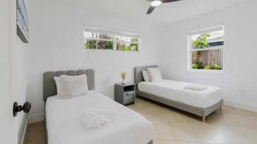 two beds in a white room with two windows at Florida Paradyse 10MIN DOWNTOWN Y 10 MIN BEACH in Fort Myers