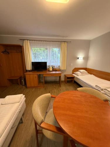 a room with a table and a bed and a desk at Motel Comet in Przeźmierowo