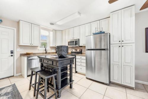 a kitchen with white cabinets and a stainless steel refrigerator at Cherry Grove Condo Steps to Beach Sleeps 8 in Myrtle Beach