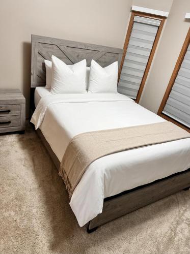 a bedroom with a large white bed with a wooden headboard at Belle-Rive - family friendly Guest House in Edmonton