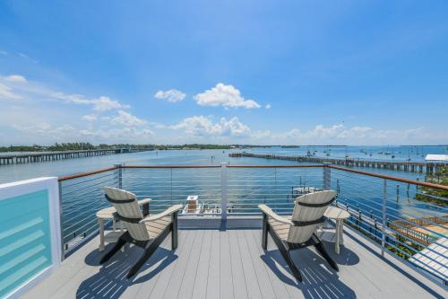 a balcony with three chairs and a pier at Bayfront Retreat in Bradenton Beach