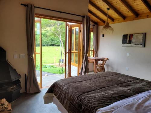 ein Schlafzimmer mit einem Bett und einer Glasschiebetür in der Unterkunft Chalé Tekoá - Aroeira, Baraúna e Juazeiro in Córrego do Bom Jesus