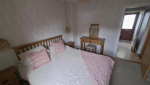 a bedroom with a bed with pink pillows and a mirror at Firthview Golspie in Golspie