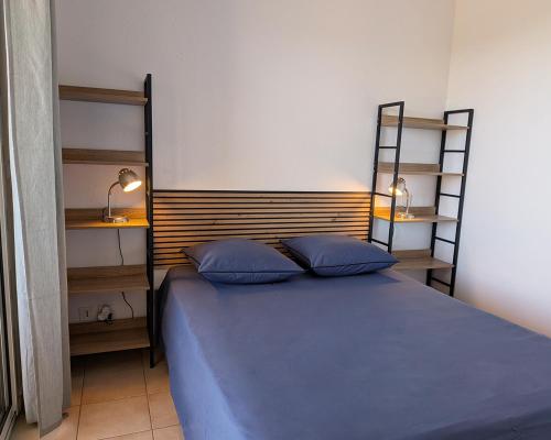 a bedroom with a bed with blue pillows and shelves at Alta Suarella in Saint-Florent