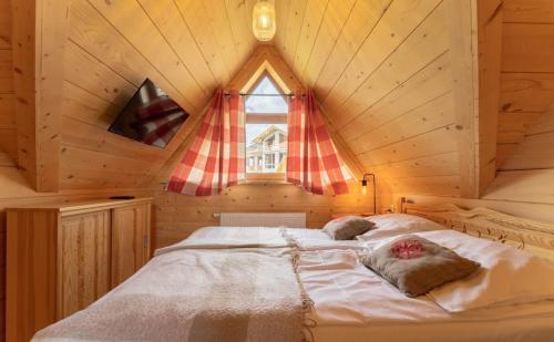 a bed in a wooden room with a window at Heidi in Zakopane
