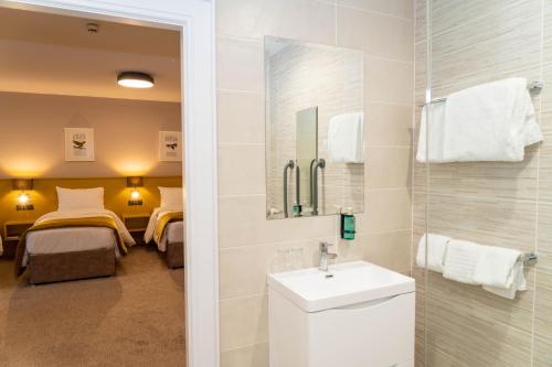 a bathroom with a sink and a mirror and a bedroom at The Carrigart Hotel in Carrigart