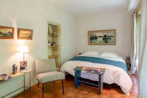 a bedroom with a bed and a chair and a table at Mas de charme - T2 et chambres d'hôtes avec piscine & jardin in Marsillargues