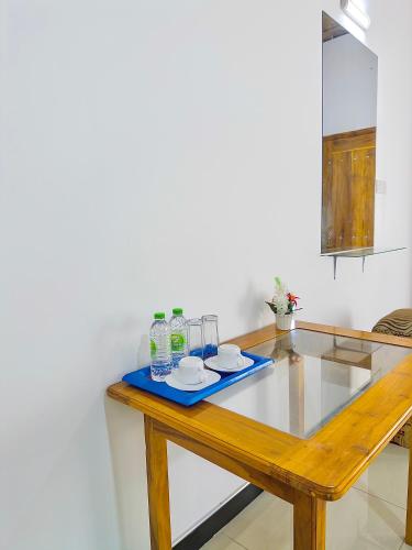 a wooden table with two plates and glasses on it at Nandana Homestay in Udawalawe