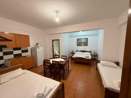 a room with two beds and a table and a kitchen at Vila Katerina Qeparo in Qeparo