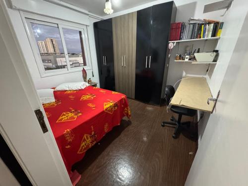 a bedroom with a red bed and a desk and a window at Conforto no Centro in Pelotas