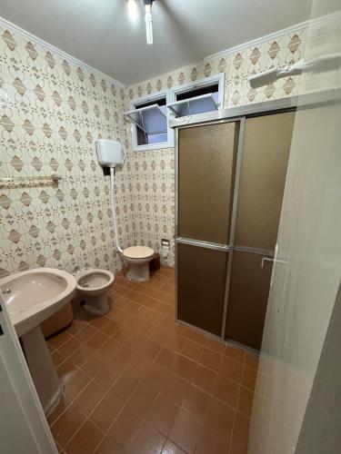 a bathroom with two toilets and a sink and a shower at Conforto no Centro in Pelotas