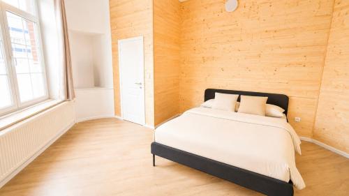 a bed in a room with a wooden wall at Daubresse 85 A Centre-Gare-Aéroport in Charleroi