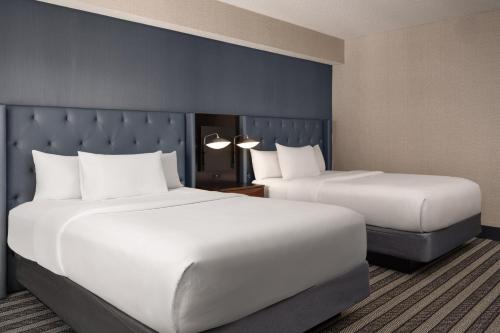 two beds in a hotel room with white sheets at Courtyard by Marriott Boston Brookline in Brookline