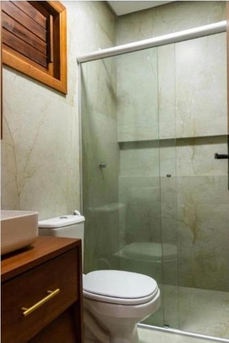a bathroom with a toilet and a glass shower at Casa Revoada BG PI in Barra Grande