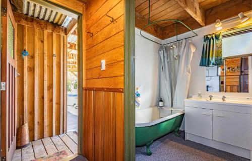 a bathroom with a green tub and a sink at Adventure Base in Ohakune