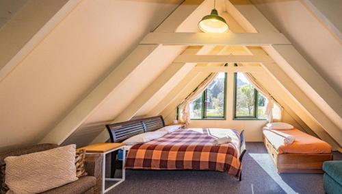 a attic bedroom with a bed and a couch at Adventure Base in Ohakune