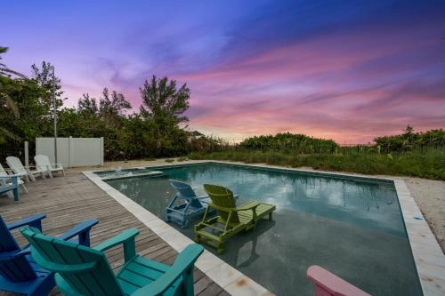 a swimming pool with chairs and a table at Beachfront Bungalow in Holmes Beach