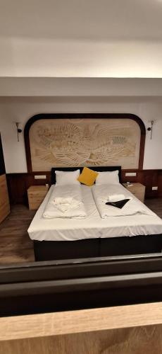 a bed with white sheets and a yellow sign on it at Smart Wellness Hotel TREZOR in Pécs