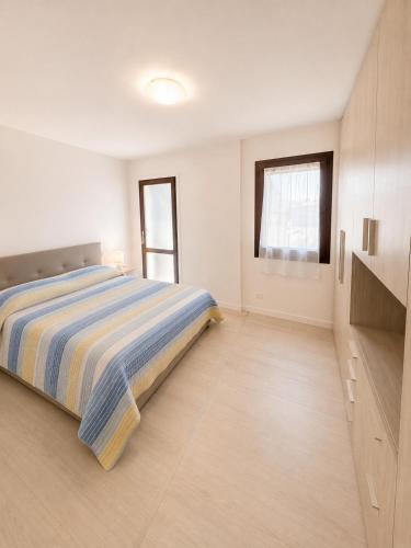 a white bedroom with a bed and a window at Casa del Marinaio - Agenzia Cocal in Caorle