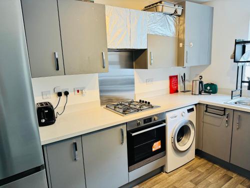 a kitchen with white cabinets and a washer and dryer at Ansari Palace in Worting