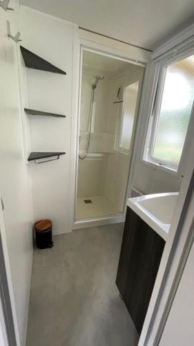 a white bathroom with a shower and a sink at Numero 281 in La Tremblade