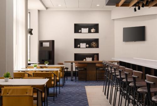 a dining room with tables and chairs and a flat screen tv at Courtyard by Marriott Boston Brookline in Brookline