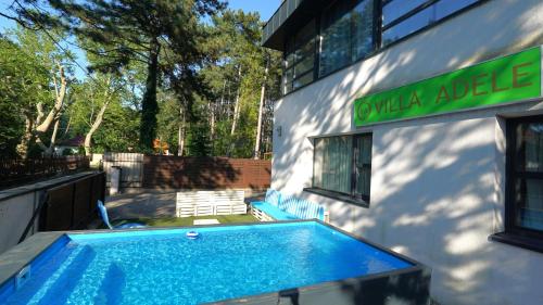 a swimming pool in front of a house at VilLa AdeLe in Siófok