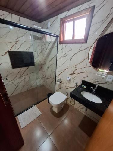 a bathroom with a shower and a toilet and a sink at Pousada Capão Fôrro in São Roque de Minas