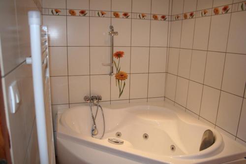 a bath tub with a flower in the corner of a bathroom at Chambres d'Hotes Les Hirondelles in Gaubiving