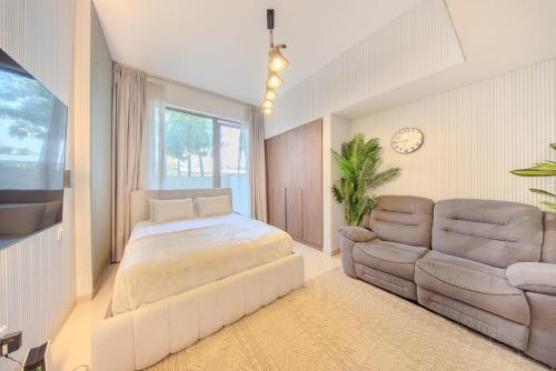 a bedroom with a bed and a couch and a chair at Luxury Studio With Private Garden - Uptown Al Zahia Sharjah in Ḩiz̧āyib az Zānah