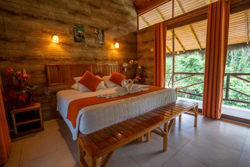 a bedroom with a bed and a bench in a room at Suchipakari Amazon Eco -Lodge & Jungle Reserve in Puerto Misahuallí