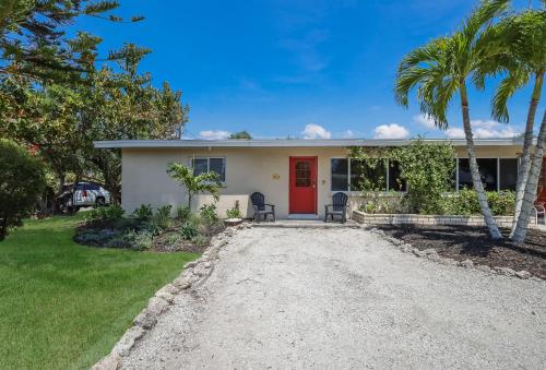 a home with a red door and palm trees at Bos Beach Bungalow in Anna Maria