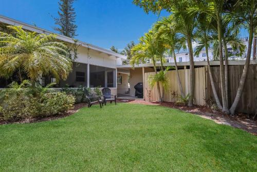 a house with palm trees and a fence at Bos Beach Bungalow in Anna Maria
