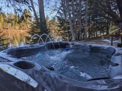 a hot tub in the middle of a pond with water at Riverfront Getaway with Hot Tub and Scenic Views in Mont-Tremblant