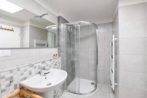 a white bathroom with a sink and a shower at Relax in Korzo Lipno in Lipno nad Vltavou