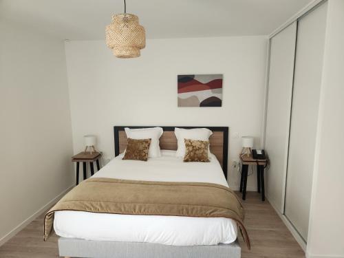 a bedroom with a large bed with white walls at DOMITYS - Les Arilles in Ifs