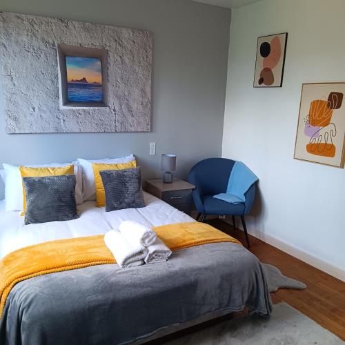 a bedroom with a bed and a blue chair at Pearly Maison Central Ruffec in Ruffec