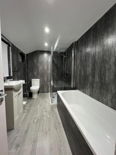 a bathroom with a tub and a sink and a toilet at Central Kettering Apartment by SJP Ideal for up to 3 Guests in Kettering