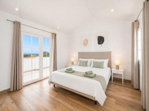 a white bedroom with a large bed and a large window at Villa Yaiza Secret 1 in Yaiza