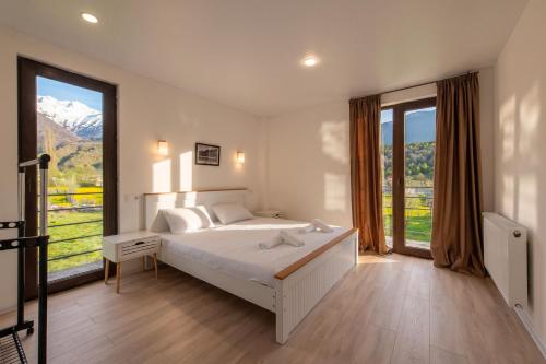 a bedroom with a white bed and a large window at Sella Mestia in Mestia