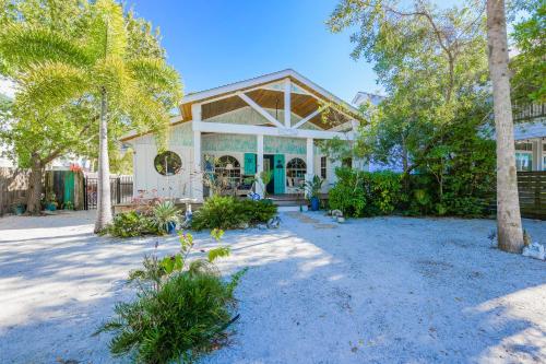 a white house with a porch with trees at Buttonwood Cottage in Anna Maria