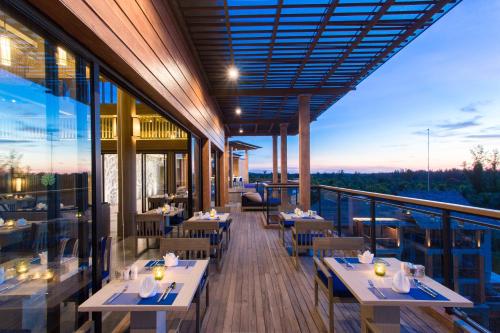 Un restaurante con mesas y sillas en un balcón. en Mai Holiday by Mai Khaolak - Adult Zone, en Khao Lak