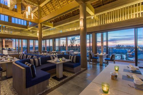 Un restaurante con sofás, mesas y ventanas. en Mai Holiday by Mai Khaolak - Adult Zone, en Khao Lak