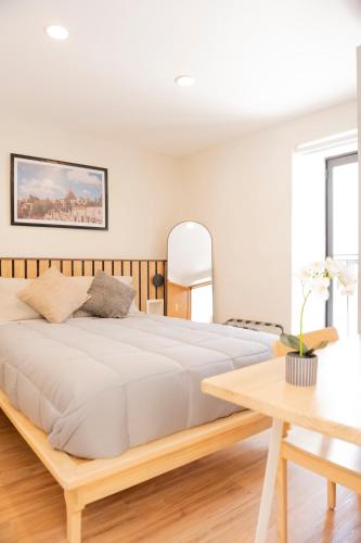 a white bedroom with a large bed and a table at Patio 7 Studios in San Miguel de Allende