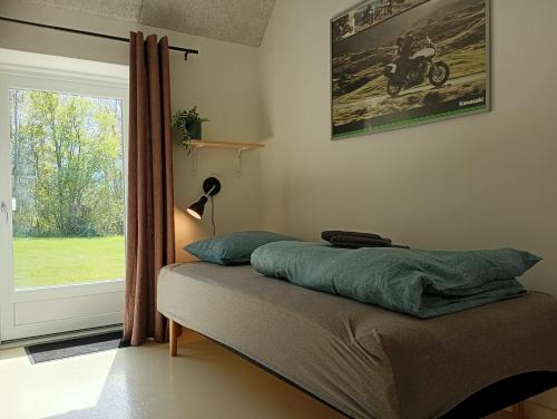 a bed sitting in a room with a window at Sønderhedens B&B in Vrå
