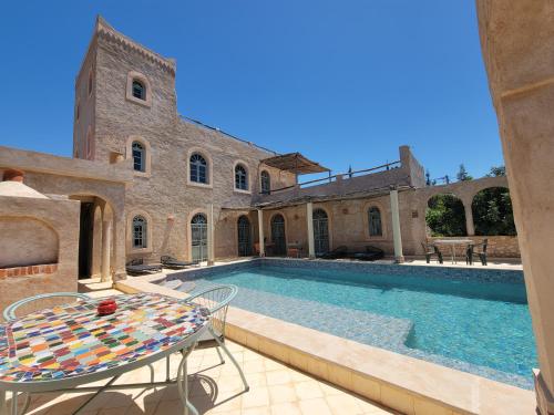 a pool with a table and chairs next to a building at Dar Ez-zine in Ounara